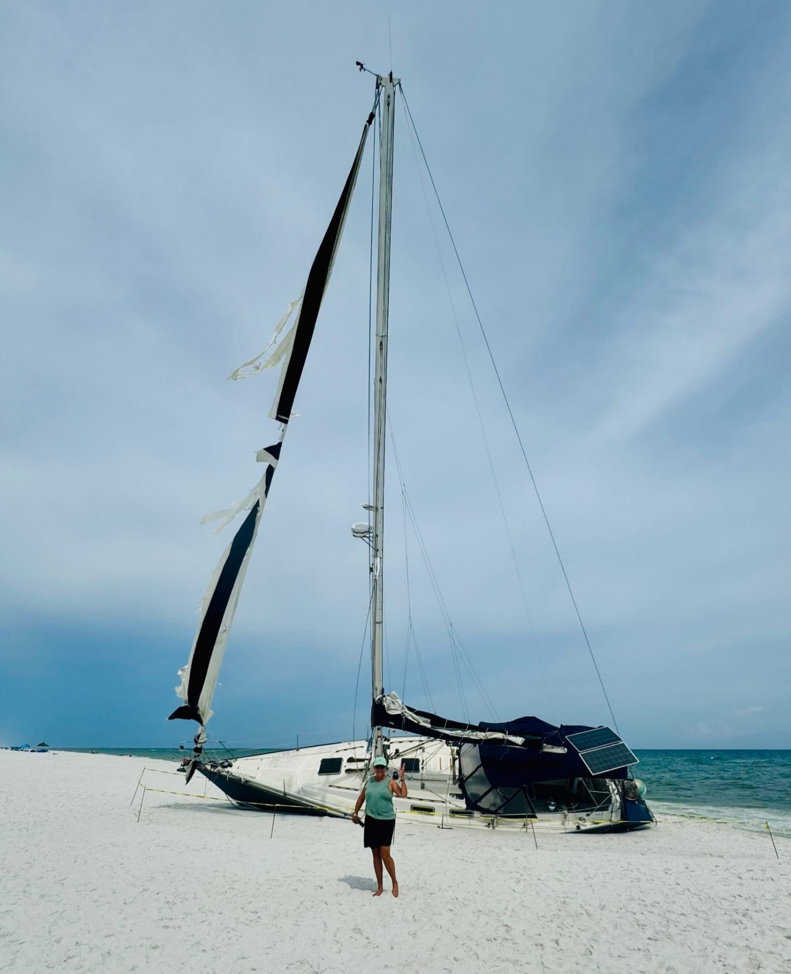Caroline standing beside a sailboat run aground on the beach — a reminder of what happens when you build on sand